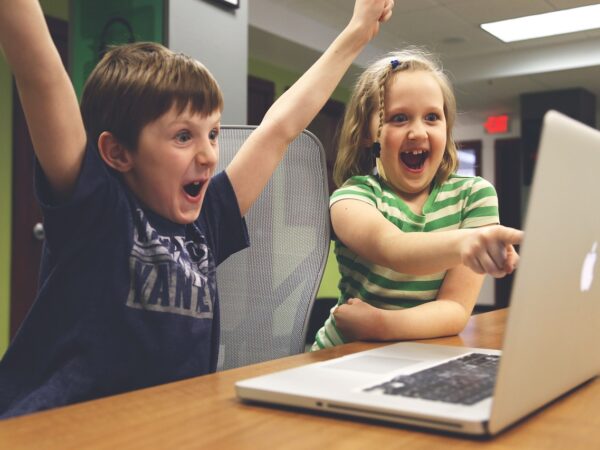 Children raising their hands in success while using a PC
