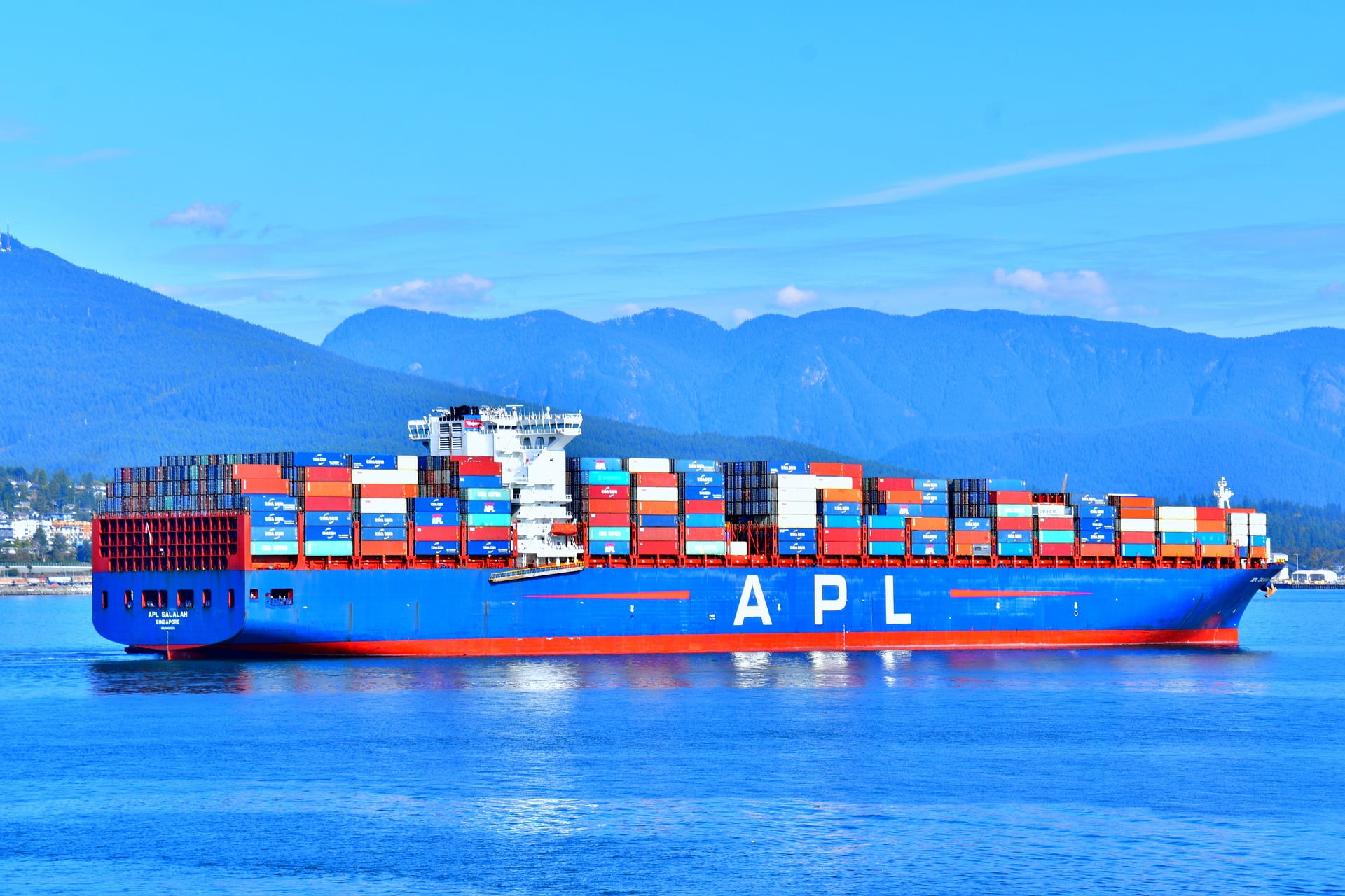 A picture of a cargo ship full of containers shipping items with a blue sky and sea