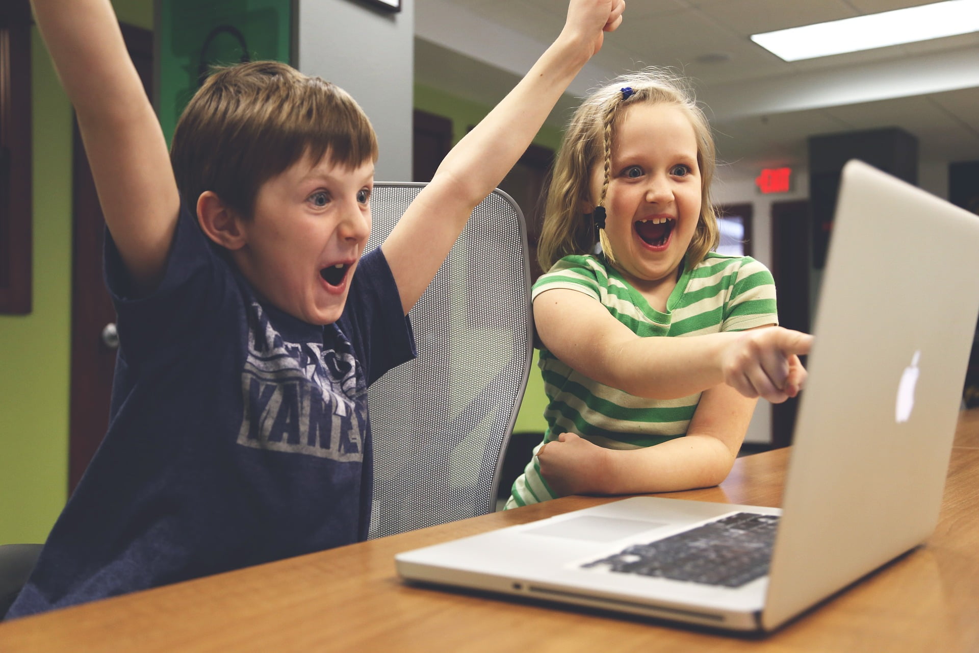 Children smiling and excited to be on a laptop